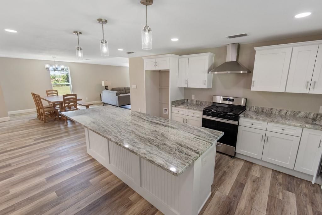 A kitchen with white cabinets , granite counter tops , stainless steel appliances and a large island.