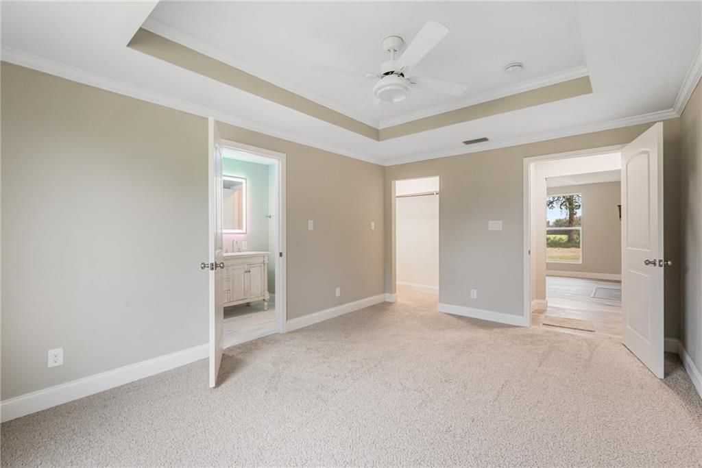 An empty bedroom with a ceiling fan and a bathroom.