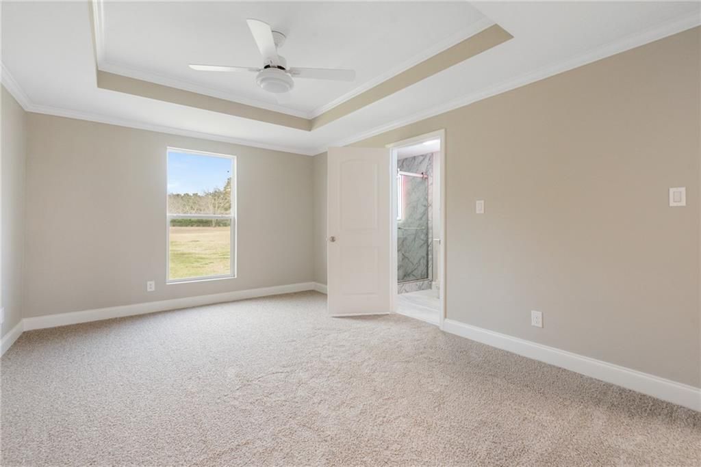 An empty bedroom with a ceiling fan and a window.