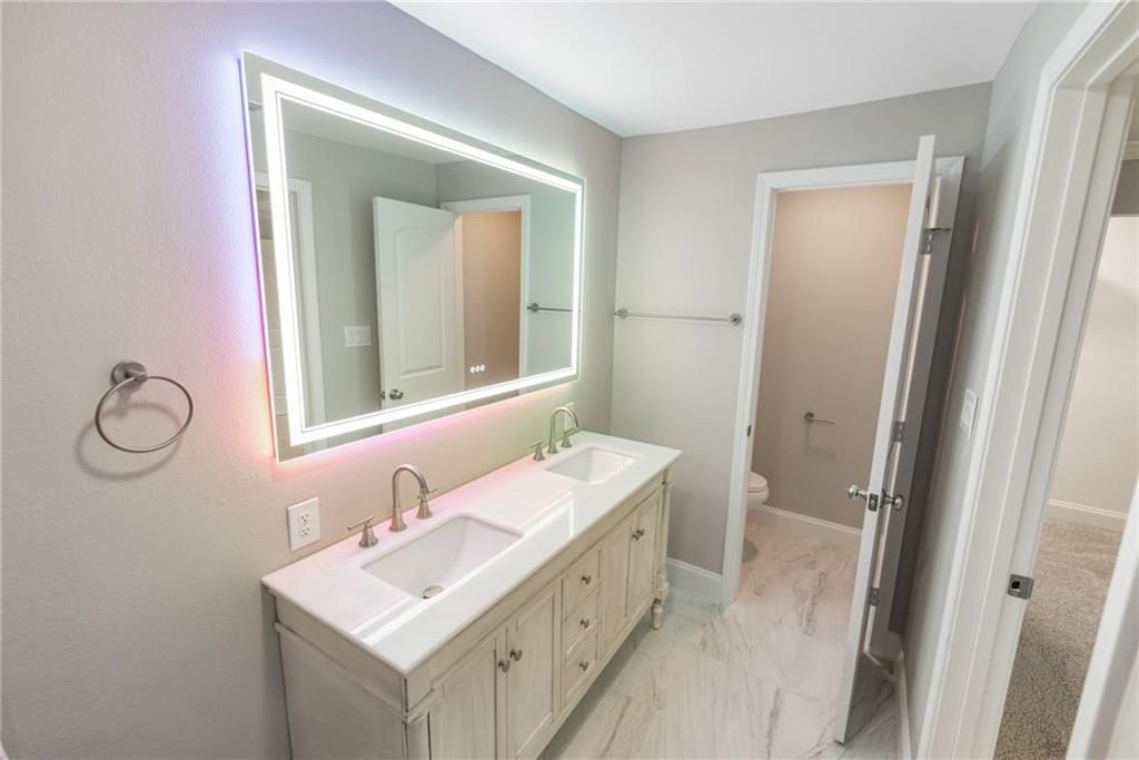 A bathroom with two sinks , a mirror and a toilet.