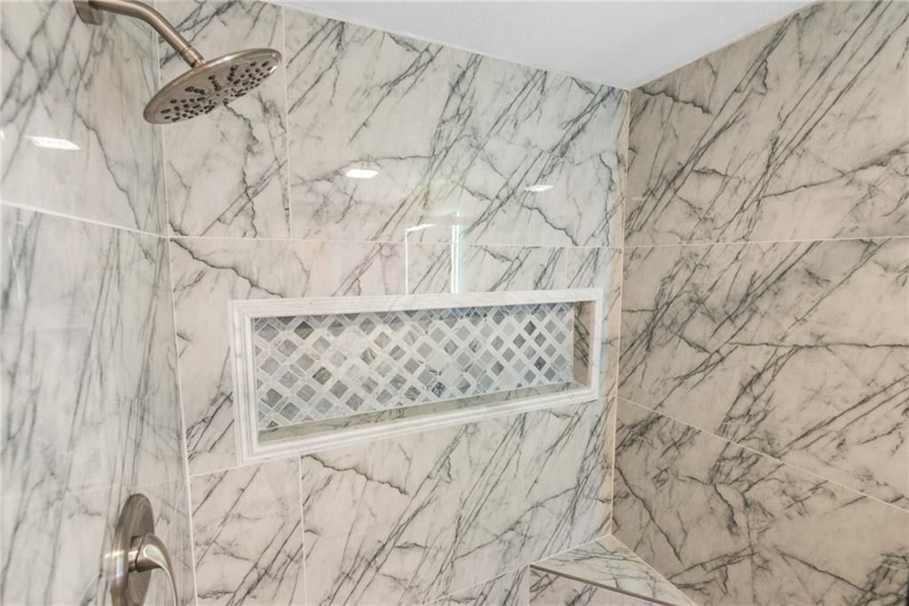 A bathroom with marble walls and a shower head.