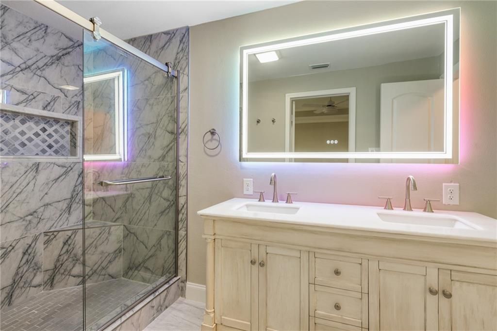A bathroom with two sinks , a shower and a large mirror.