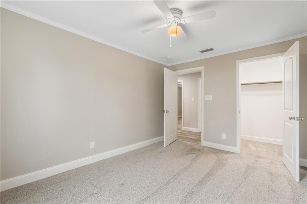 An empty bedroom with a ceiling fan and a walk in closet.