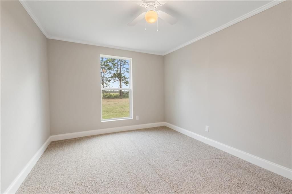 An empty bedroom with a window and a ceiling fan.