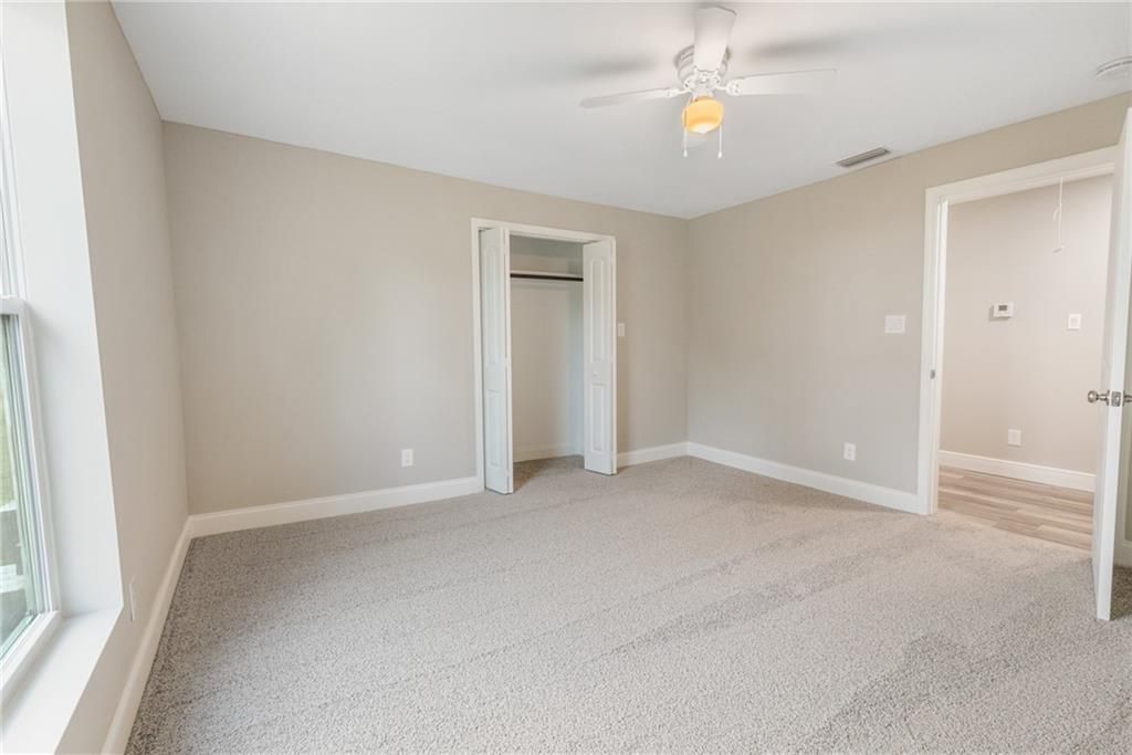 An empty bedroom with a ceiling fan and a window.