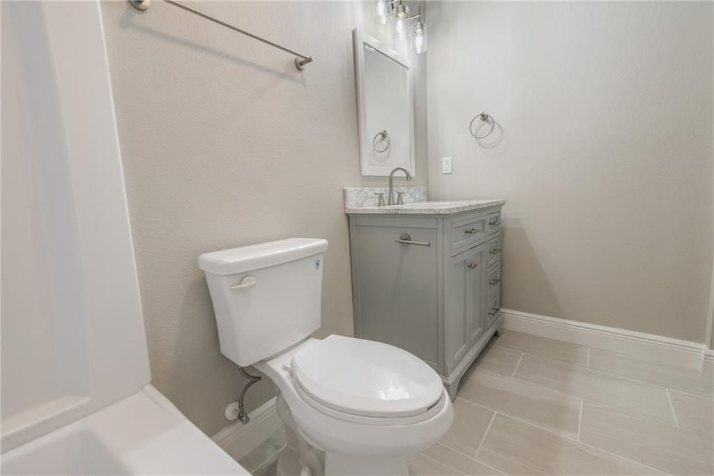 A bathroom with a toilet , sink and mirror.