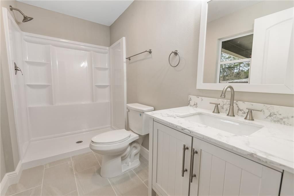 A bathroom with a toilet , sink and shower.