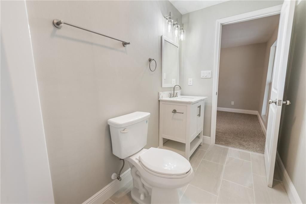 A bathroom with a toilet , sink and mirror.