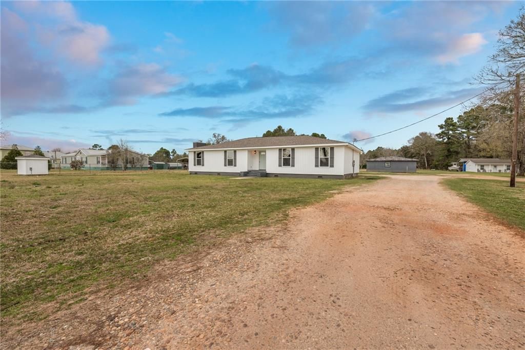 A dirt road leading to a house in the middle of a field.