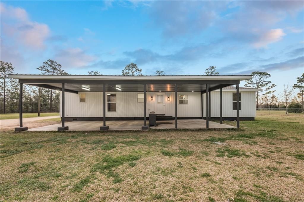 A white mobile home with a covered porch in a field.