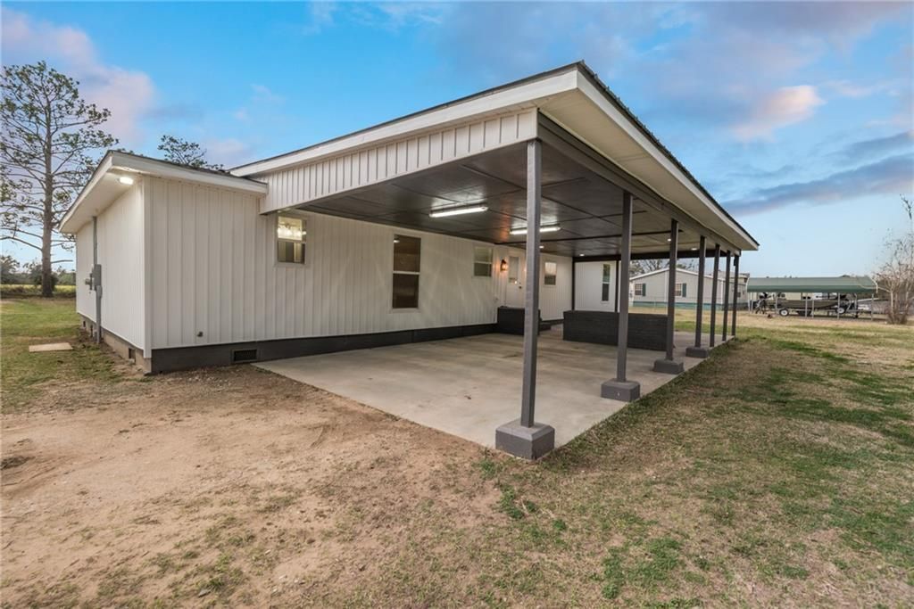 A white mobile home with a carport in front of it.