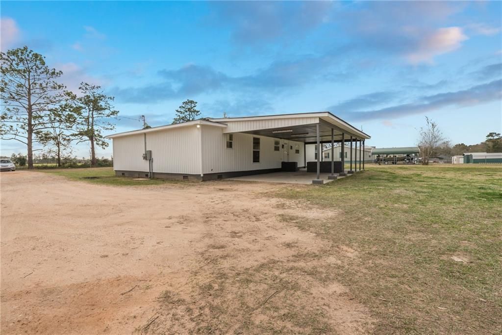 A white house is sitting in the middle of a dirt field.