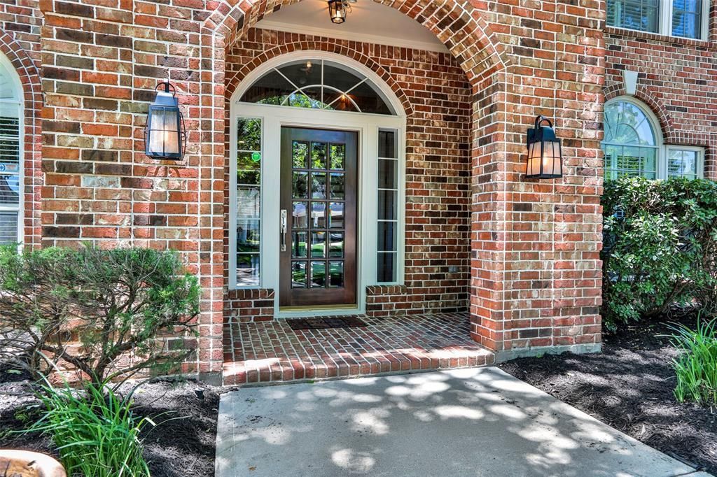 The front door of a brick house with a walkway leading to it.