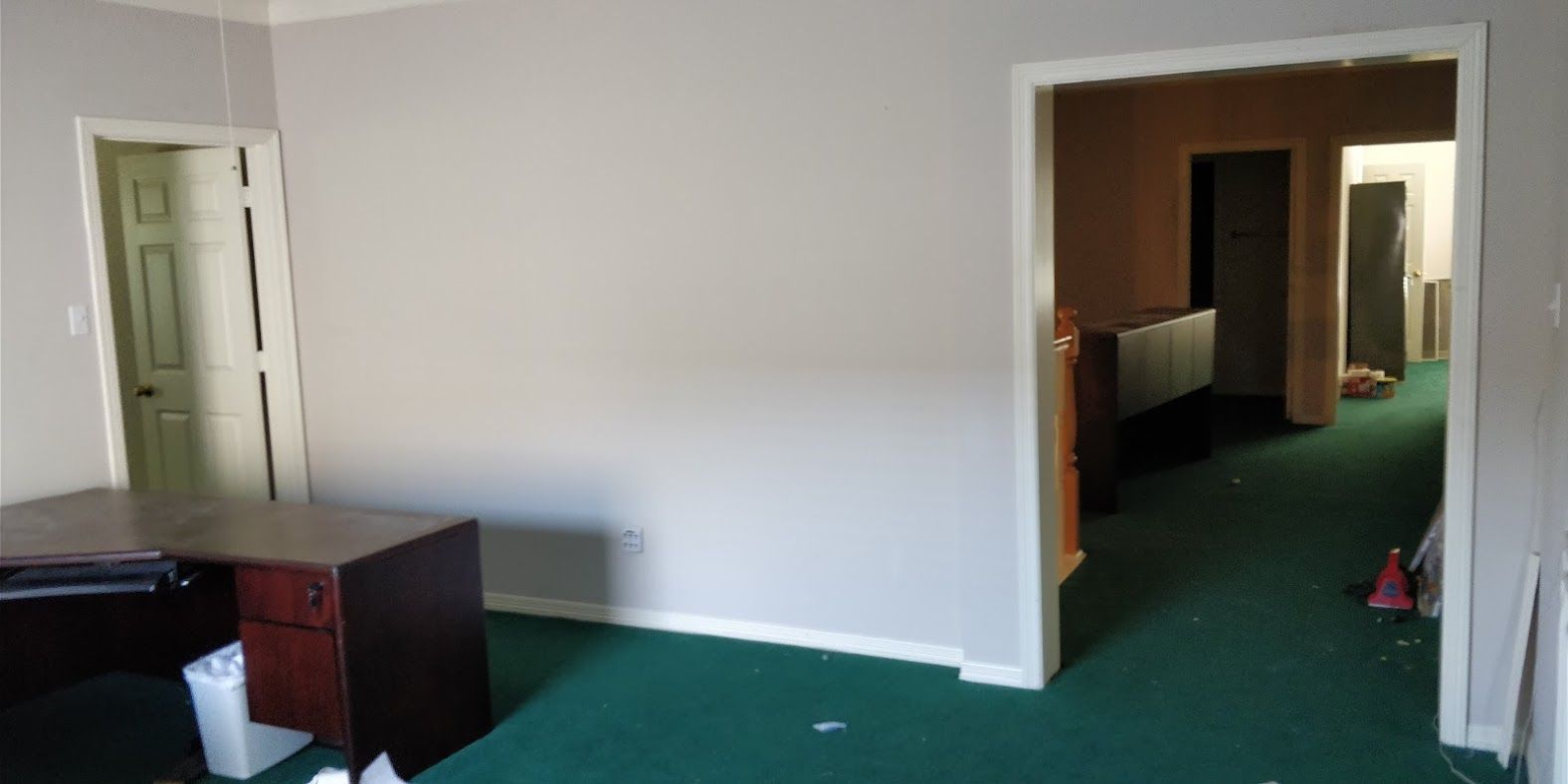 An empty room with a desk and a green carpet.