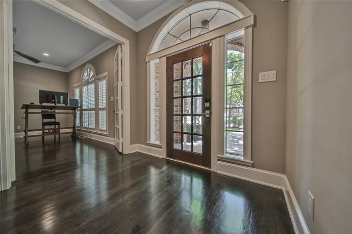A hallway in a house with a wooden floor and a wooden door.