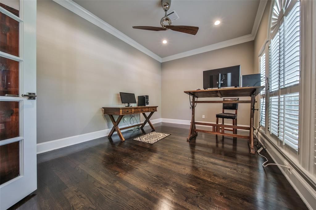 There is a ceiling fan in the room with a desk and chairs.