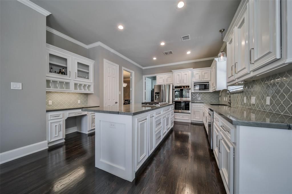 A kitchen with white cabinets, granite countertops, and hardwood floors.