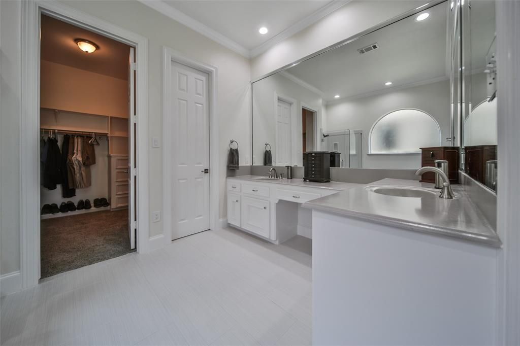 A bathroom with a sink, mirror and walk in closet.