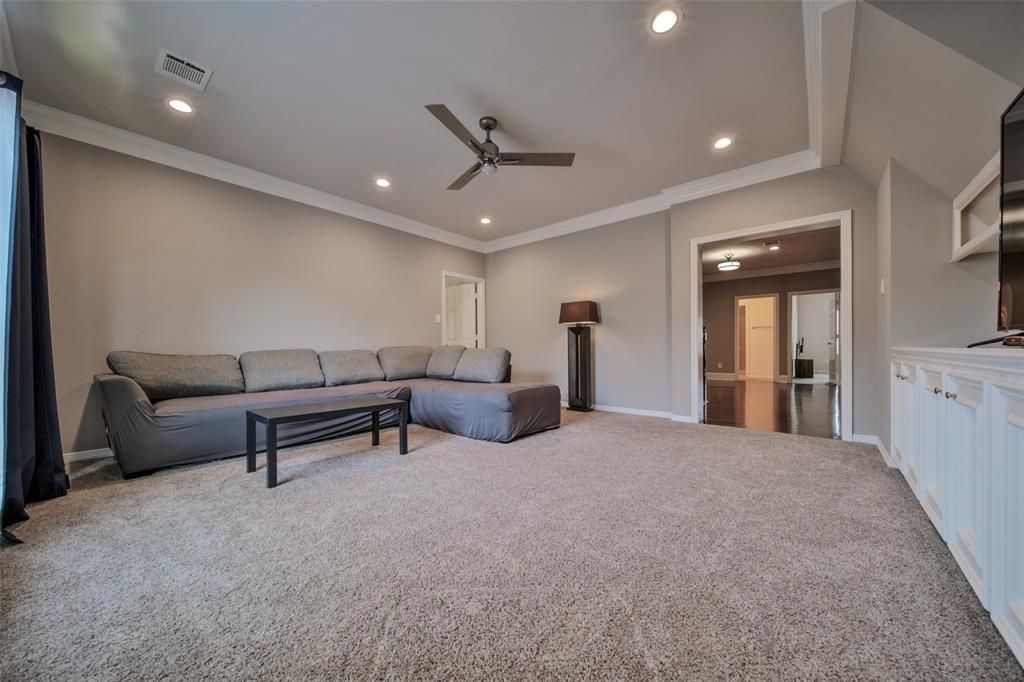 A living room with a large sectional couch and a ceiling fan.