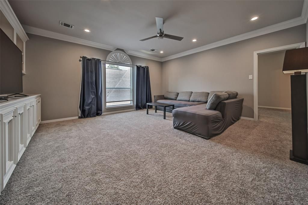 A living room with a large sectional couch and a ceiling fan.