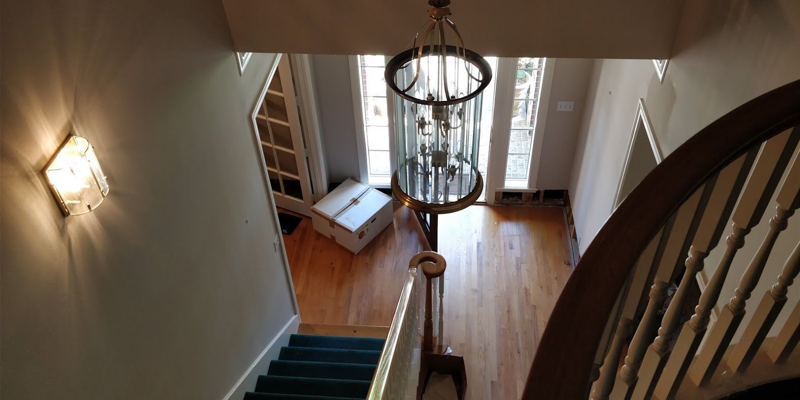 An aerial view of a staircase in a house with a chandelier hanging from the ceiling.