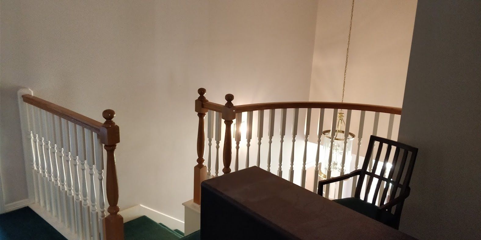 A staircase with a wooden railing and a chair.