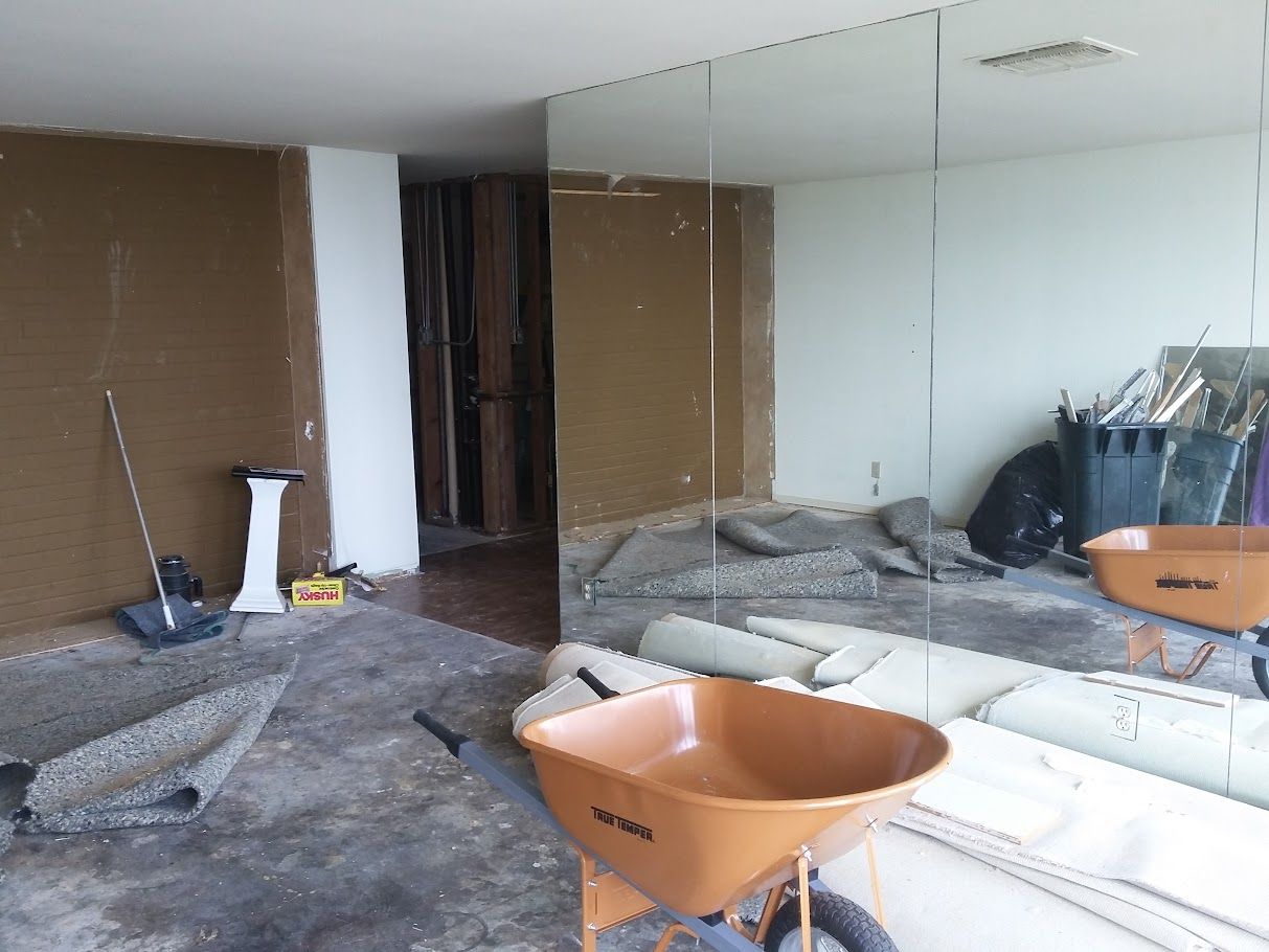 A wheelbarrow is sitting in front of a large mirror in a room.
