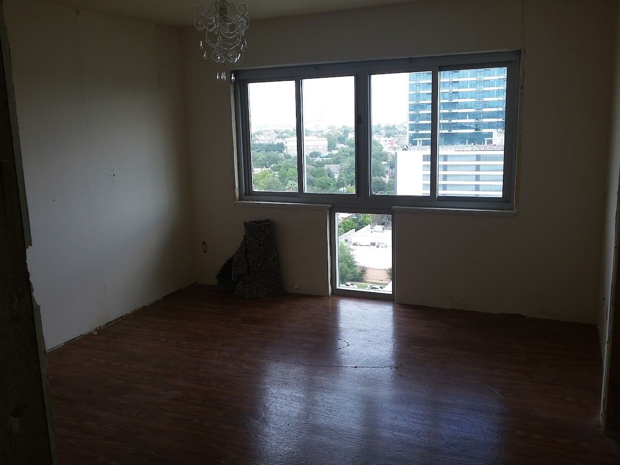 An empty room with a large window and a chandelier