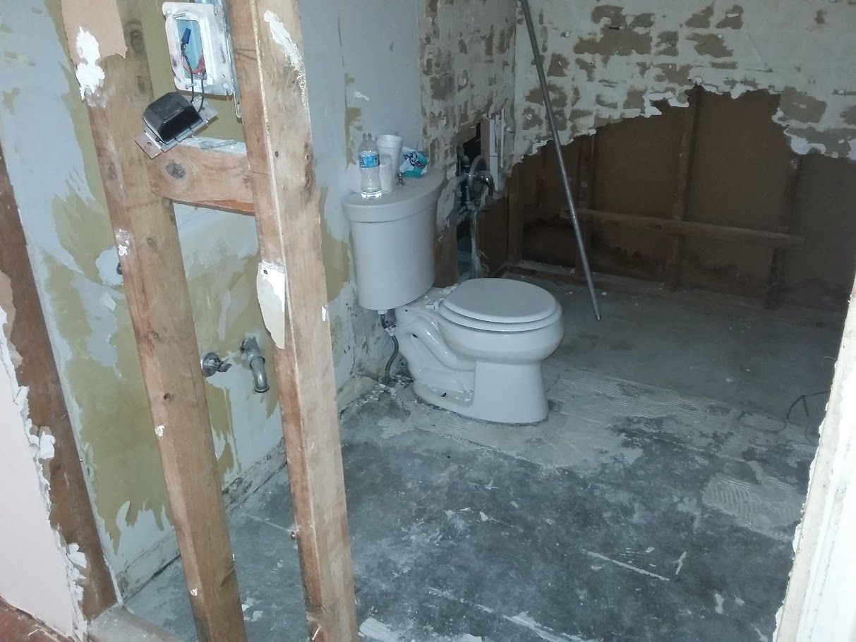 A toilet in a bathroom with a hole in the wall