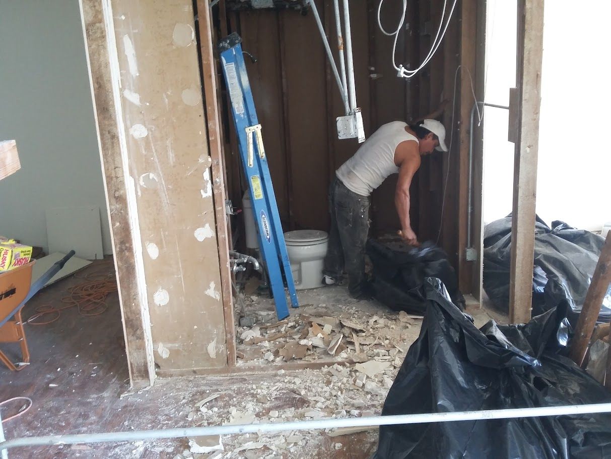 A man is working in a room with a ladder and a toilet.