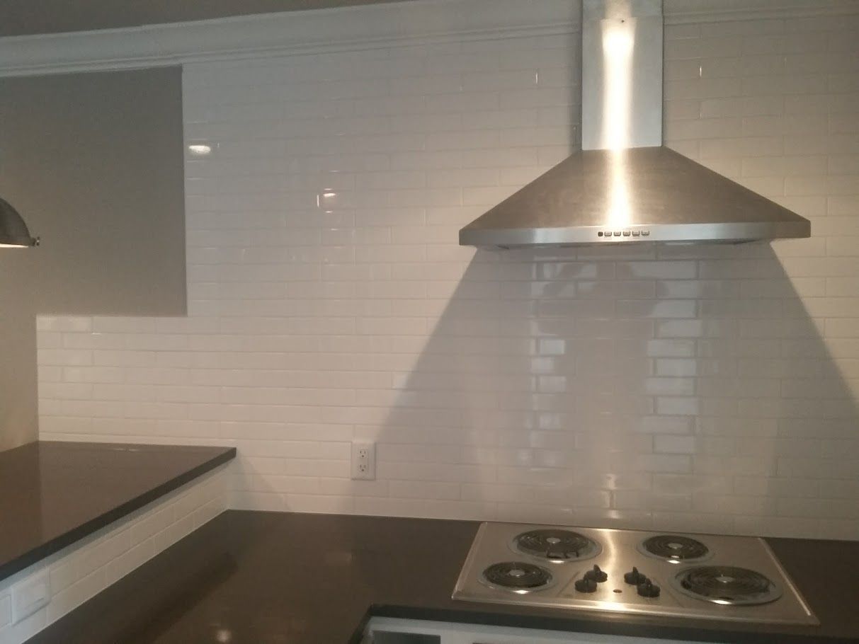A kitchen with a stove top oven and a hood above it.