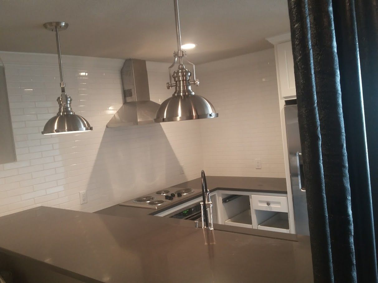A kitchen with stainless steel pendant lights hanging from the ceiling