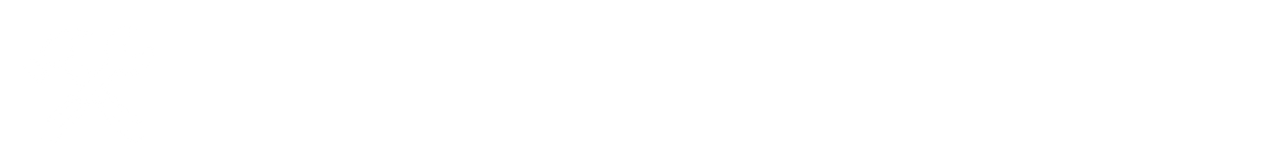 A clear glass of amber liquid with ice cubes and a sprig of mint on a wooden table.