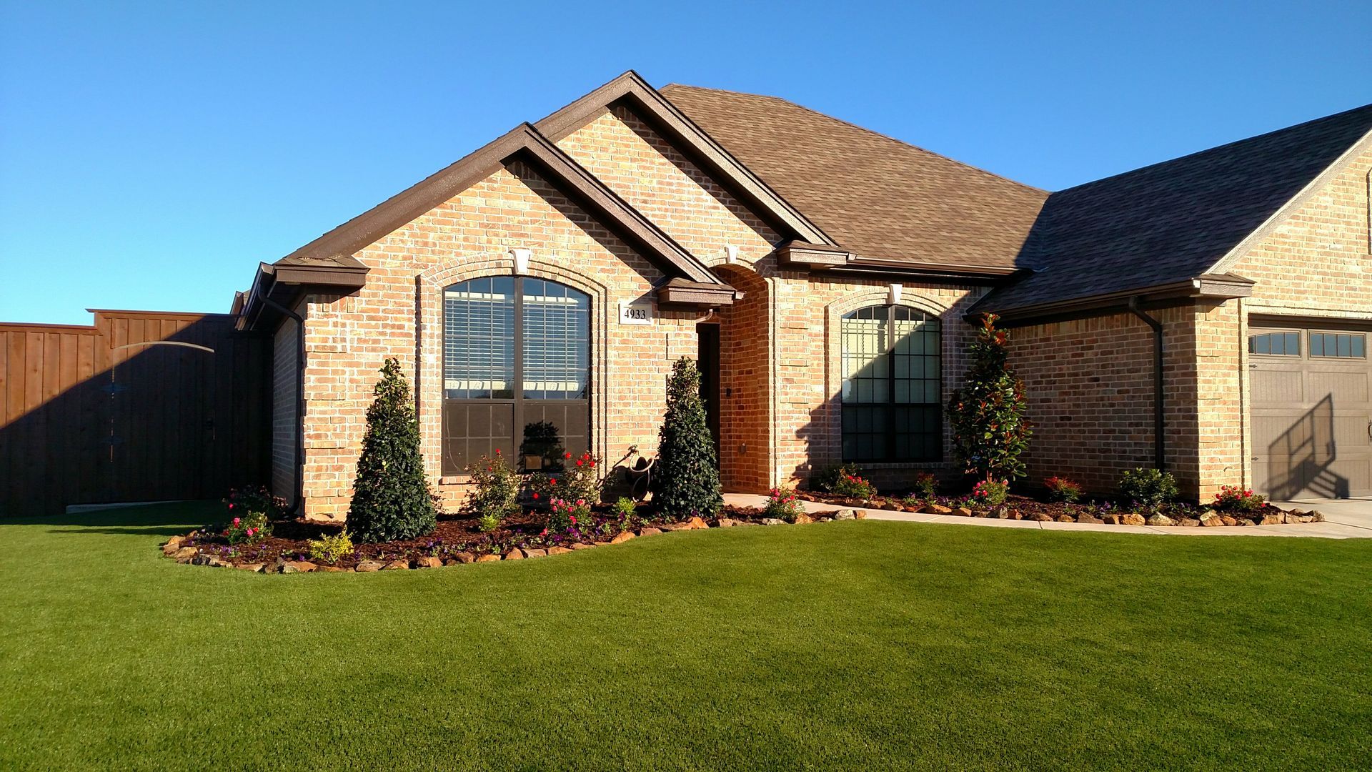 A brick house with a lush green lawn in front of it