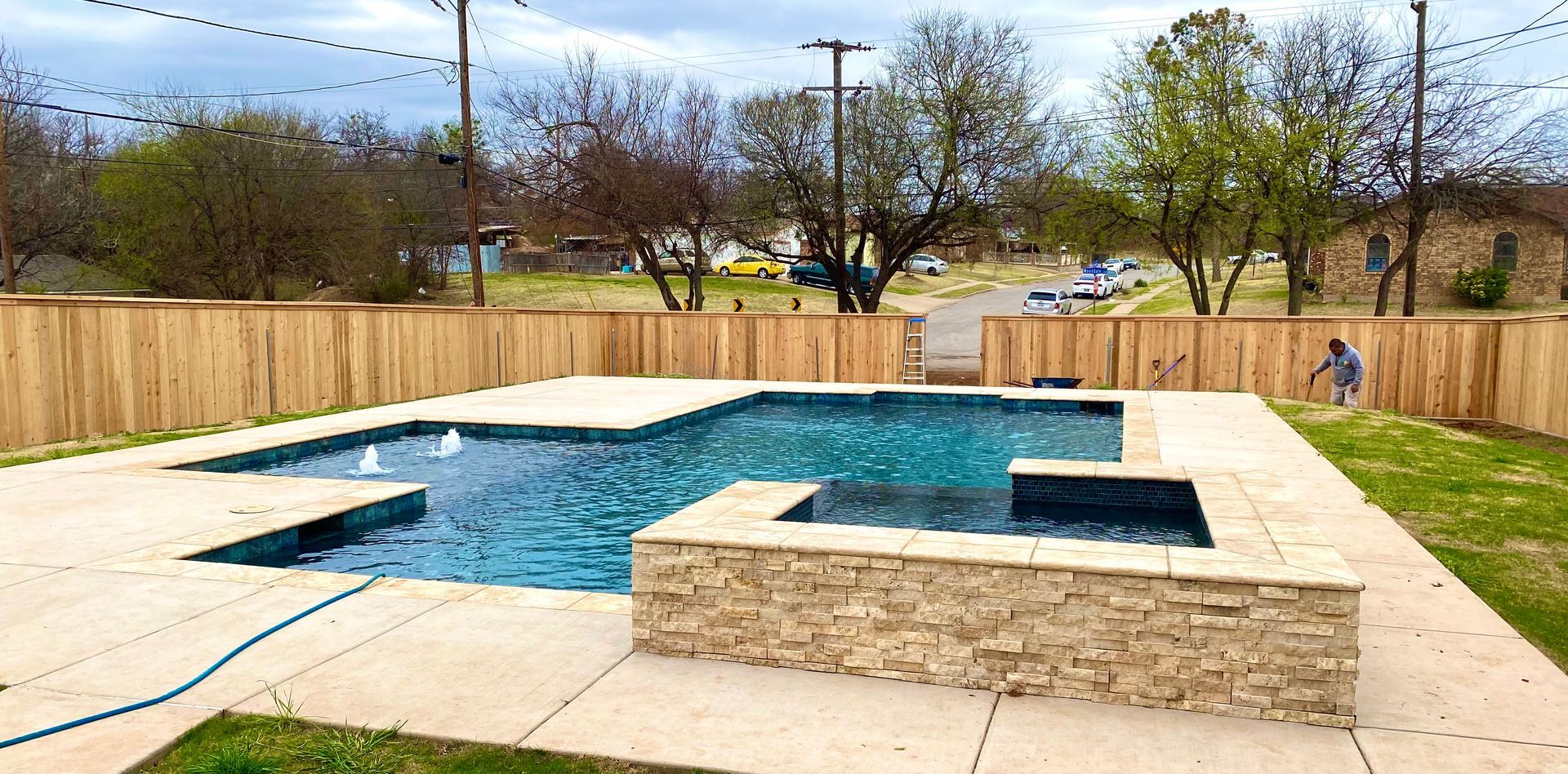 A large swimming pool is surrounded by a wooden fence.