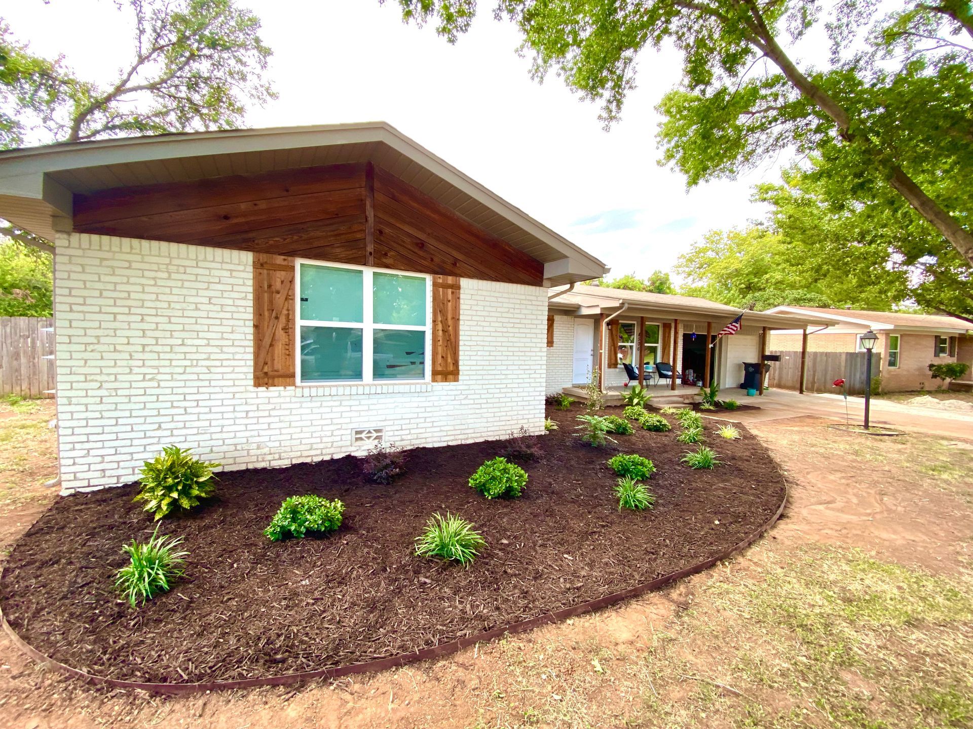 A white brick house with a lot of plants in front of it.