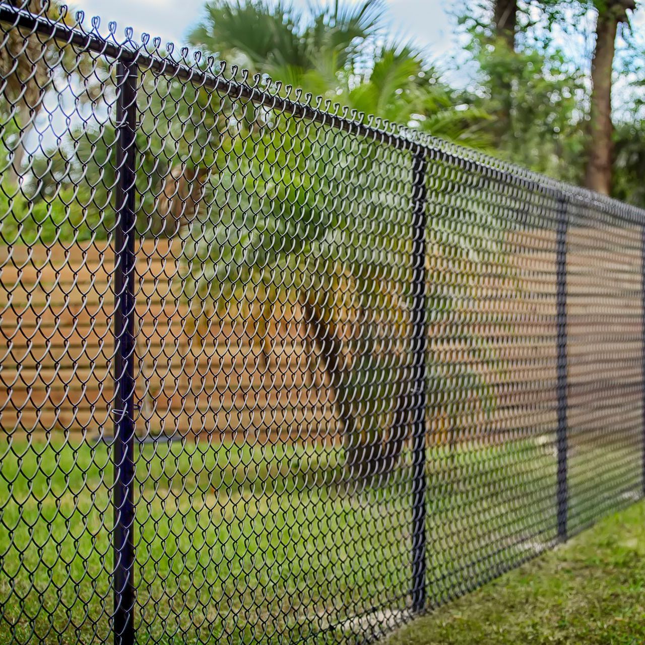 a chain link fence with a wooden fence behind it