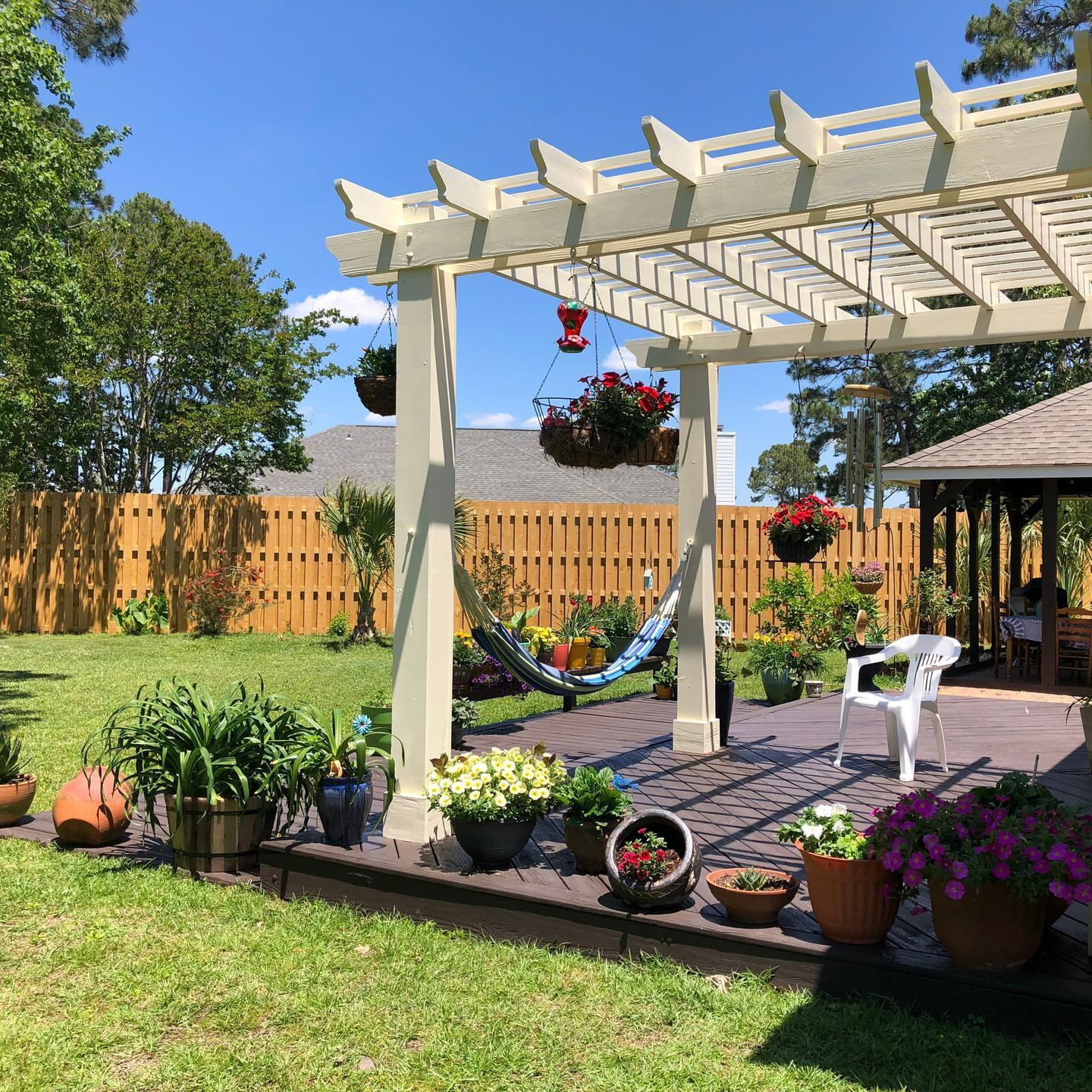 a backyard with a white pergola and a hammock
