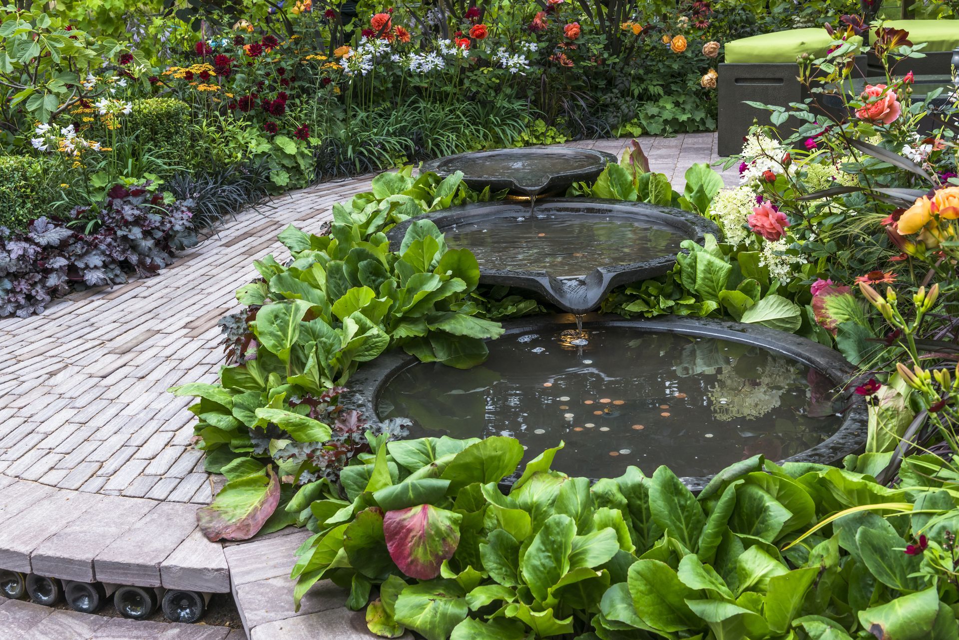 a garden with a fountain surrounded by plants and flowers