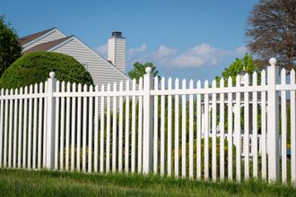 a white picket fence with a house in the background