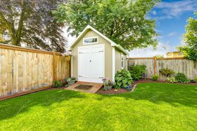a small shed in a backyard with a wooden fence