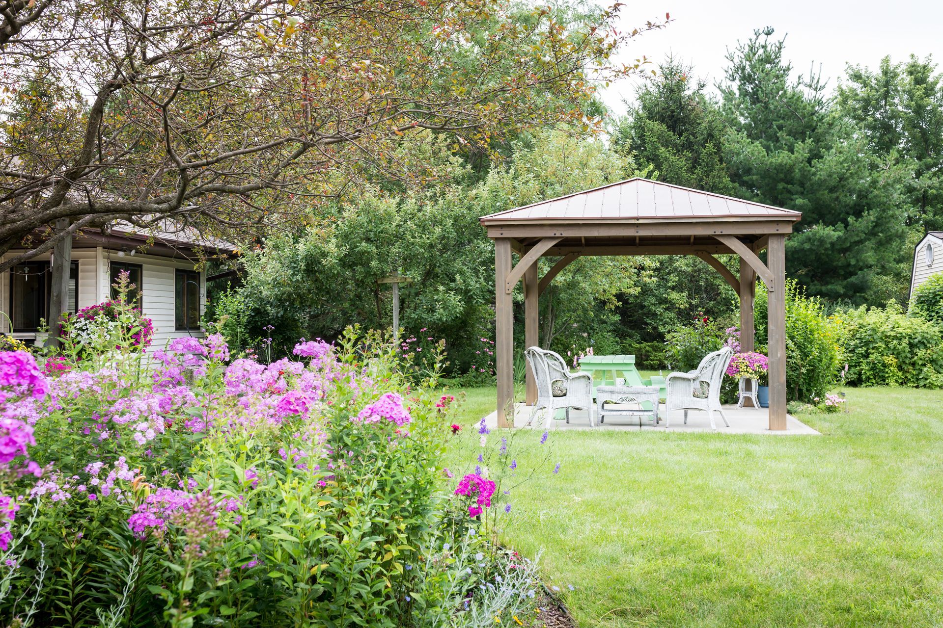 a gazebo sits in the middle of a lush green garden