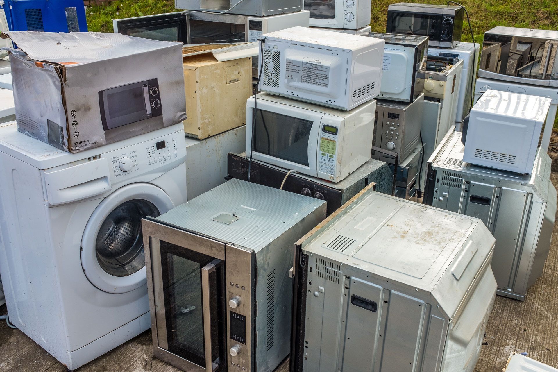 Pile of old washing machines and appliance cabinets stacked outdoors in a scrapyard