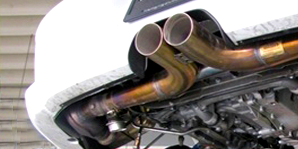 A white car with two exhaust pipes coming out of it