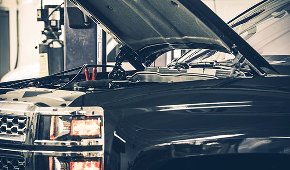 A black truck with its hood open in a garage.