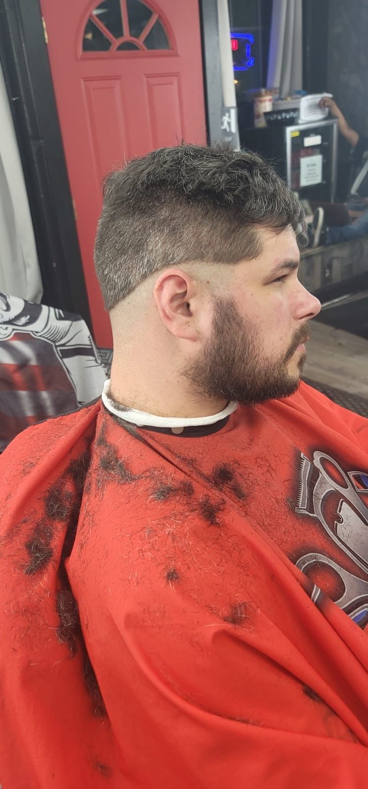 A man with a fade haircut, featuring an intricate design, is in a barber shop.