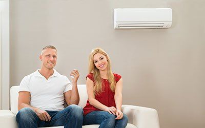 Couple On Sofa Using Air Conditioner - HVAC Contractors in Lebanon, MO