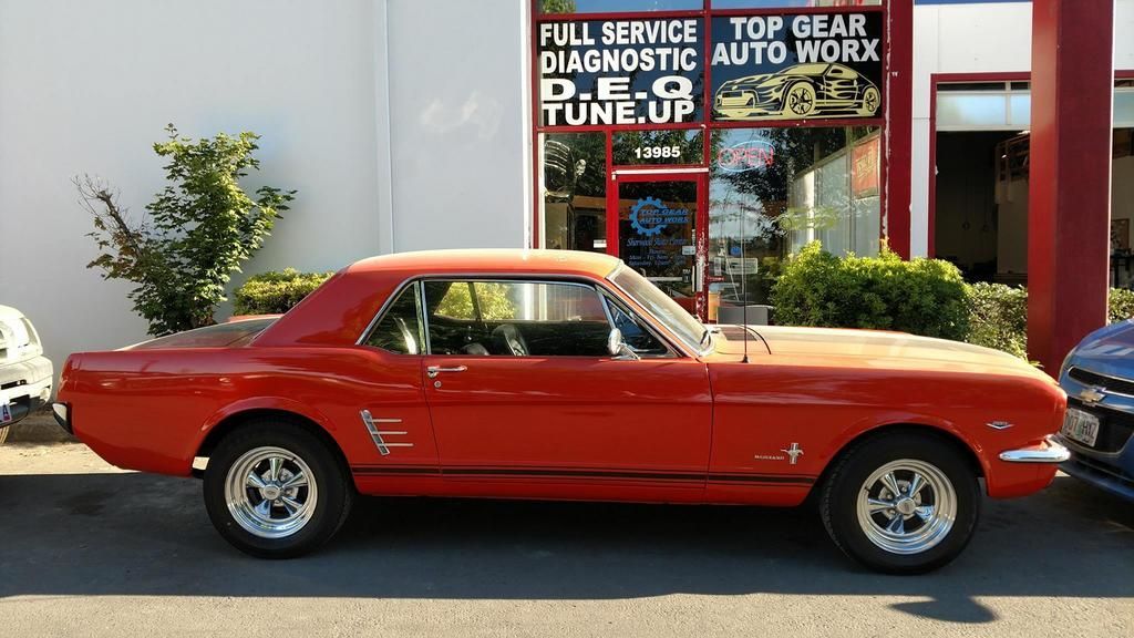 A red car is parked in front of a store that offers full service diagnostic auto work