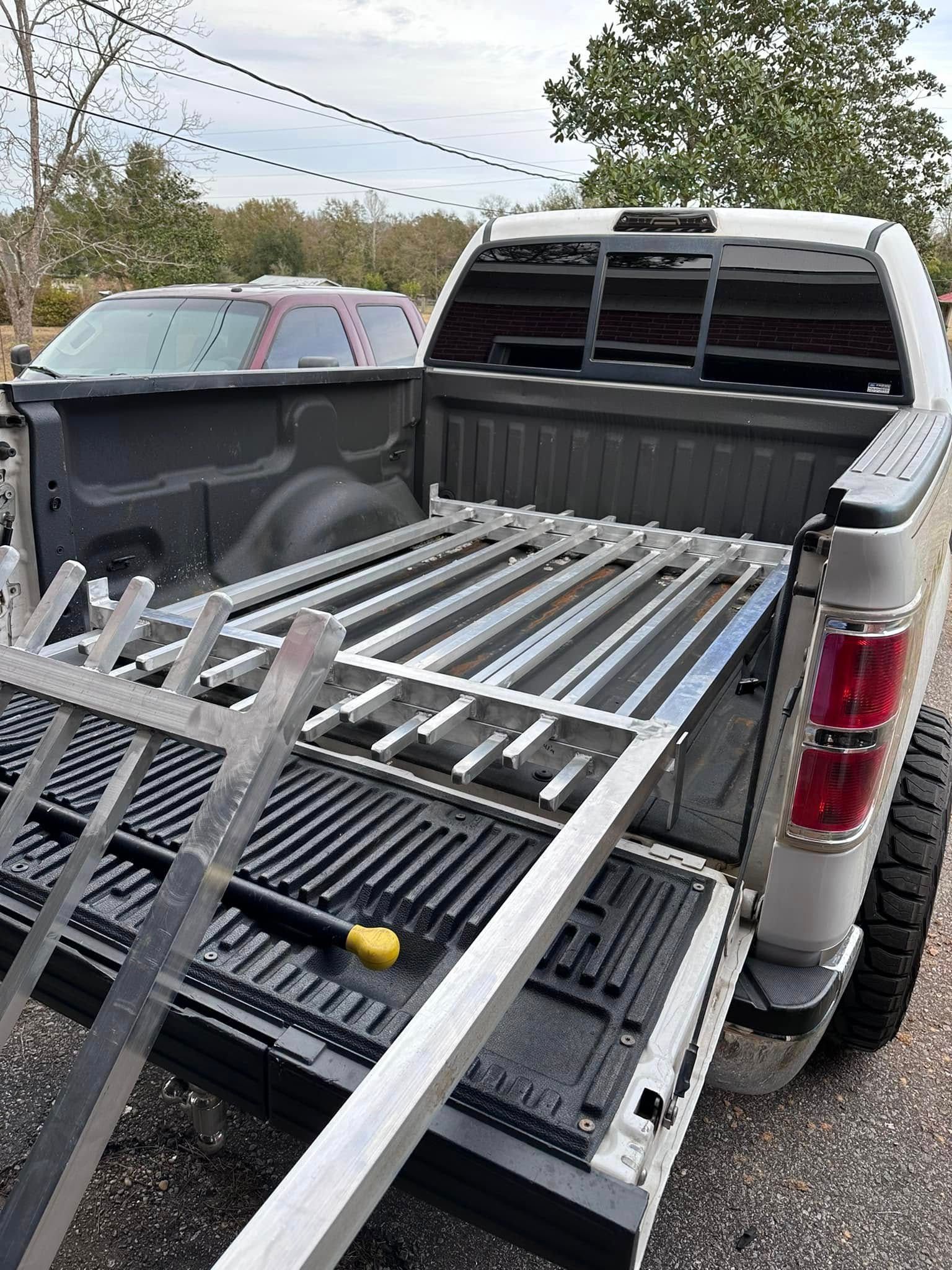 White pickup truck bed with aluminum ramps inside, parked outdoors.