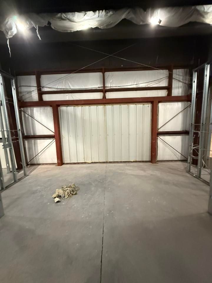 Interior of a construction site with steel framework, a concrete floor, and insulation.